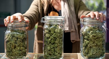 Glass jar full of Cannabis Sativa for sale at a market stall.