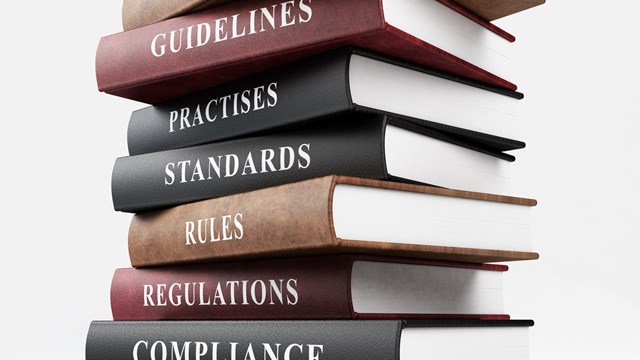 Leather covered book of compliance. Stack of books on top of each other with business words written on their spines. Isolated on white background with clipping path.