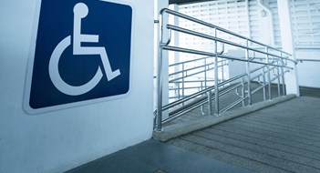 Universal Design & the ADA Concret ramp way with stainless steel handrail with disabled sign for support wheelchair disabled people.