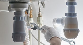Identifying & Dealing With Plumbing Issues Plumbing work theme. Hand with wrench tighten screw on pipe