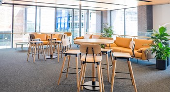 Pandemic Design Meeting area in a modern creative coworking office space with couch, sofa, bar stools, leaner tables, carpet. No people, modern building interior. Photographed in Auckland, New Zealand, NZ.