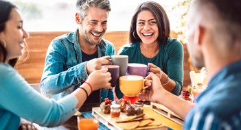 People group toasting latte at coffee bar rooftop - Friends talking and having fun together at cappuccino restaurant - Life style concept with happy men and women at cafe terrace - Bright warm filter