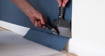 Maintaining Your Hallways Man cutting wallpaper. Maintenance repair works renovation in the flat. Restoration indoors.