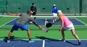 Pickleball! colorful action image of two couples playing pickleball in a mixed doubles match