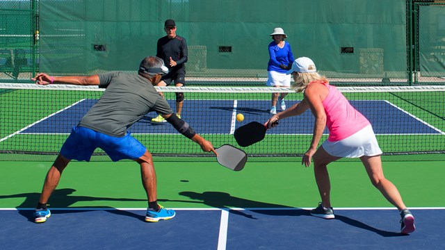 colorful action image of two couples playing pickleball in a mixed doubles match