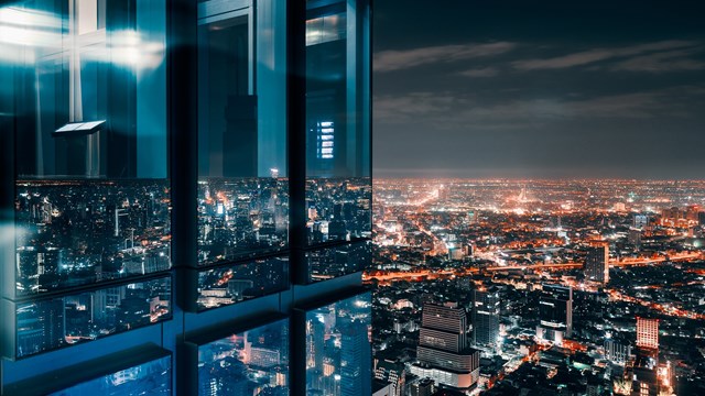 Corner glass window with glowing crowded city