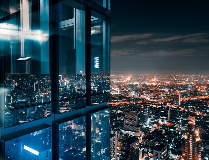 Corner glass window with glowing crowded city