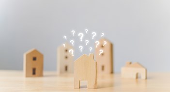 Another Year of Modest Growth for U.S. Condos & HOAs in 2024 Real estate developer and managing property investment concept. Selective focus wooden houses with question mark on wood table