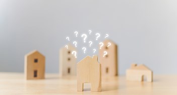 Real estate developer and managing property investment concept. Selective focus wooden houses with question mark on wood table