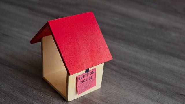 Closeup image of toy house and eviction notice.