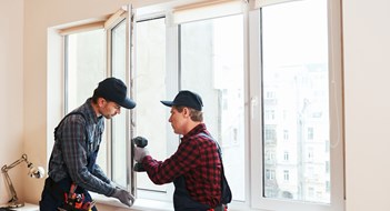Minimizing the Impact of Major Renovations Quality light. Construction workers installing new window in house together