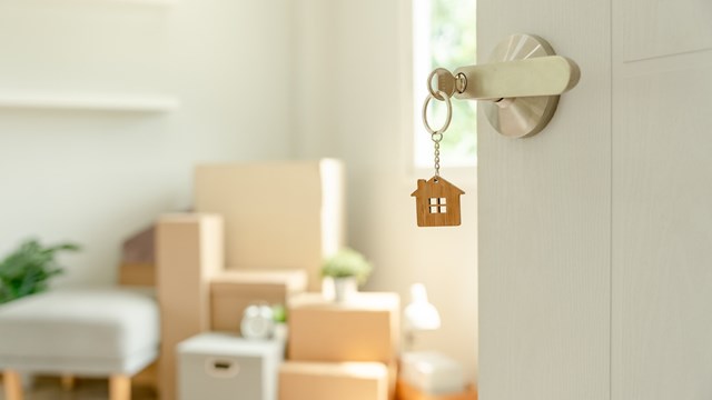 Moving house, relocation. The key was inserted into the door of the new house, inside the room was a cardboard box containing personal belongings and furniture. move in the apartment or condominium